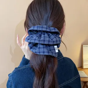 Detailed macro view of a stylish blue plaid double-layer fabric scrunchie for hair