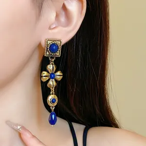 Detailed close-up of vintage gold floral drop earring with blue lapis stones on ear