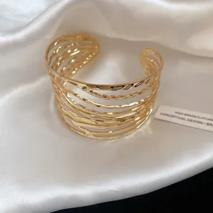 Macro view of wide gold-colored cuff bracelet with multi-layered twisted lines