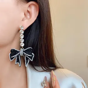 Gros plan détaillé d'une boucle d'oreille pendante avec un nœud en strass noir sur un mannequin.