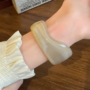Close-up of a vintage cream marbled irregular resin open bangle on wrist.