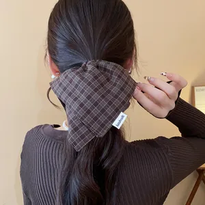Close-up of a brown plaid fabric scrunchie with handmade label on a ponytail