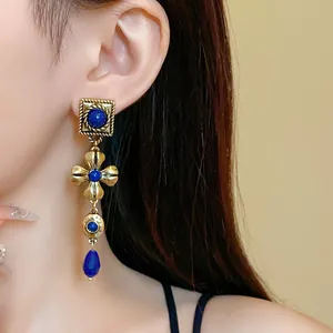 Detailed view of vintage long teardrop earrings featuring blue stones and gold finish.