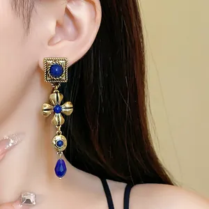Close-up detail of vintage palace style long drop earrings with blue stone on model