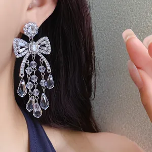 Close-up detail of an elegant silver bow-shaped drop earring with sparkling zircon tassels.