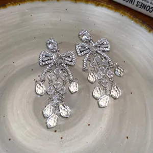 Elegant silver-toned bowknot earrings with sparkling clear zircon tassels on a ceramic plate