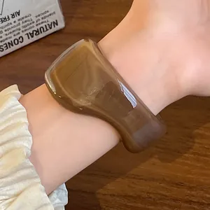 Close-up detail of a vintage irregular amber-colored resin open bangle on a wrist