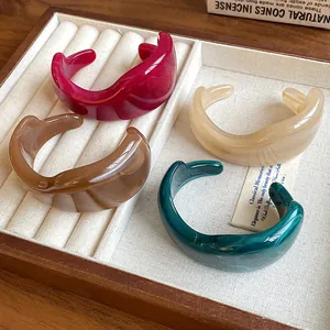 Close-up of four irregular marbled resin open bangles in diverse vintage colors