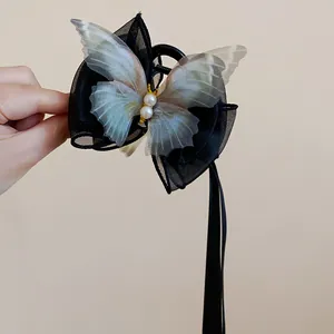 Detailansicht einer schwarzen Schmetterlings-Haarklammer mit Perlenmitte und langen Bändern.