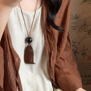 Neo-Chinese style retro pendant necklace with black bead on a linen garment background