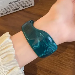 Detailed view of an irregular emerald green marbled resin cuff bracelet on a wrist