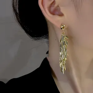 Elegant gold leaf tassel earrings for women shown worn on ear with metallic shine