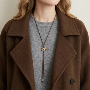 Detailed view of a vintage wooden rocking horse necklace on a warm brown sweater.