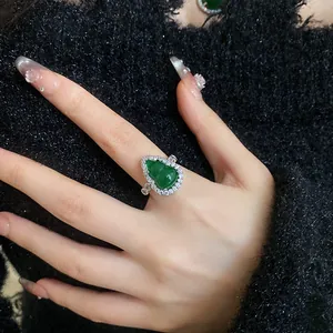Detail of a vintage green hulu resin ring with sparkling zircons on a black fabric background.
