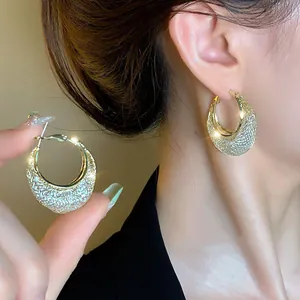 Detailed view of elegant golden textured geometric basket hoop earrings worn by a model.