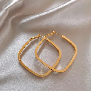 Detailed view of square geometric hoop earrings with a polished gold finish and silver needles