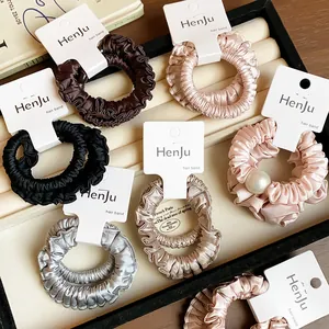 Macro view of various colored pleated satin scrunchies with cards in a jewelry tray