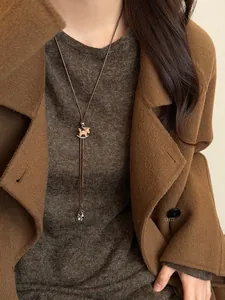 Detailed view of a retro Maillard style rocking horse pendant necklace on a brown sweater