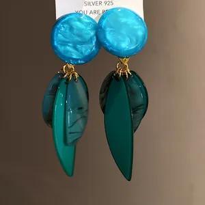 Vue détaillée des boucles d'oreilles en résine bleue et verte avec tiges en argent S925.