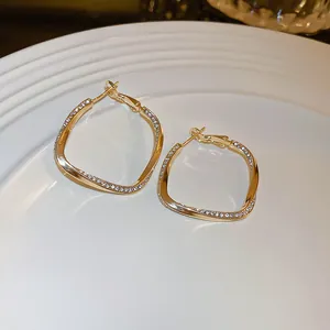 Close-up detail of elegant gold geometric hoop earrings with sparkling rhinestones on plate