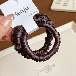 Close-up of brown pleated satin scrunchies with elegant sheen and high elasticity.