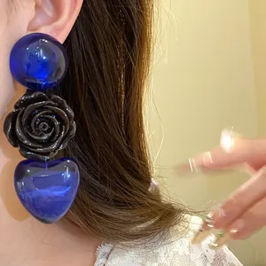Détail en gros plan des boucles d'oreilles en résine avec cœur bleu et rose noire