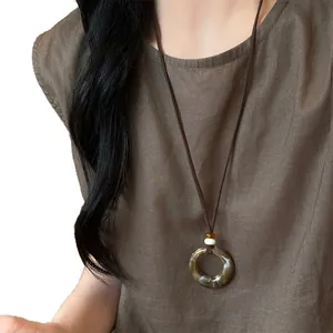 Minimalist retro resin circle pendant necklace with long brown cord shown on model