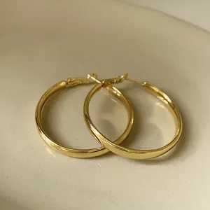 Close-up of minimalist gold geometric hoop earrings with polished metallic finish