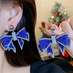 Sparkling blue resin bow earrings with rhinestone outlines and silver needle post.