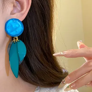 Vue détaillée de boucles d'oreilles pendantes en résine bleue et feuilles sarcelle
