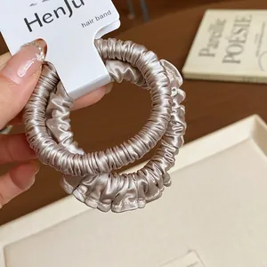 Close-up of champagne satin pleated elastic hair scrunchies on display card