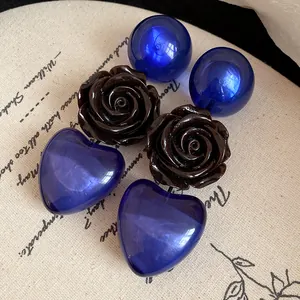 Détail rapproché de boucles d'oreilles rose en résine et cœur bleu sur un tissu vintage