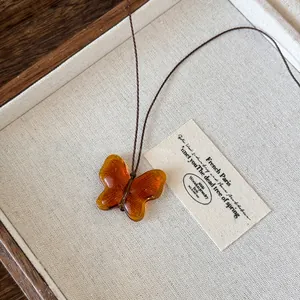 Close-up of vintage amber translucent resin butterfly pendant on brown cord