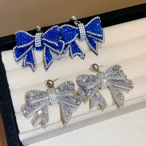 Detail view of sparkling blue and silver rhinestone-encrusted resin bow earrings