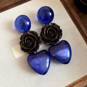 Gros plan de boucles d'oreilles en résine avec cœurs bleus et roses foncées.