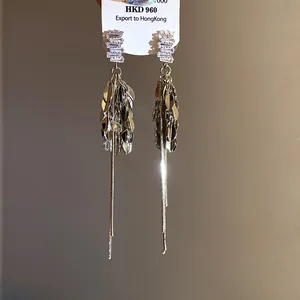Primo piano di eleganti orecchini a nappa d'argento con borchie di zircone scintillanti
