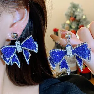 Detailed macro view showing the sparkling blue rhinestone on the elegant bow earrings