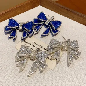 Macro detail of elegant resin bow earrings featuring sparkling rhinestone accents