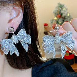 Detailed view of sparkling rhinestone-encrusted bow earrings with elegant silver needles.