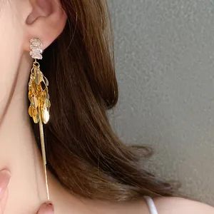 Elegante primo piano di orecchini dorati con nappine a spiga e zirconi brillanti