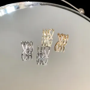 Close-up of interlaced multi-layer zircon ear cuffs with reflection on a mirror surface