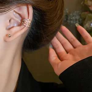 Close-up view of a stylish gold multi-layer zircon ear cuff earring on a model's ear