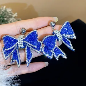 Macro view of elegant royal blue resin bow earrings featuring delicate rhinestone edging