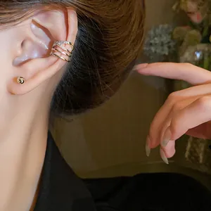 Detailed close-up showing a stylish layered crisscross zircon ear cuff on ear cartilage.