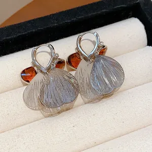Close-up of retro glass petal tassel earrings with silver finish and amber accents.