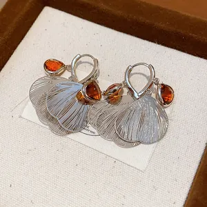 Detail view of vintage silver petal earrings with faceted amber glass stones in a box.