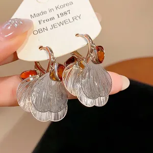 Detail view of vintage silver petal tassel earrings with amber glass stones on OBN card