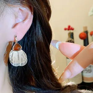 Detail shot of vintage amber glass and white petal fringe earrings worn by model