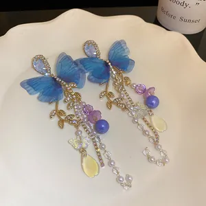 Detailed view of blue mesh butterfly earrings with golden leaves and pearl tassels