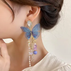 Close-up detail of blue mesh butterfly tassel earring with pearls and crystals.